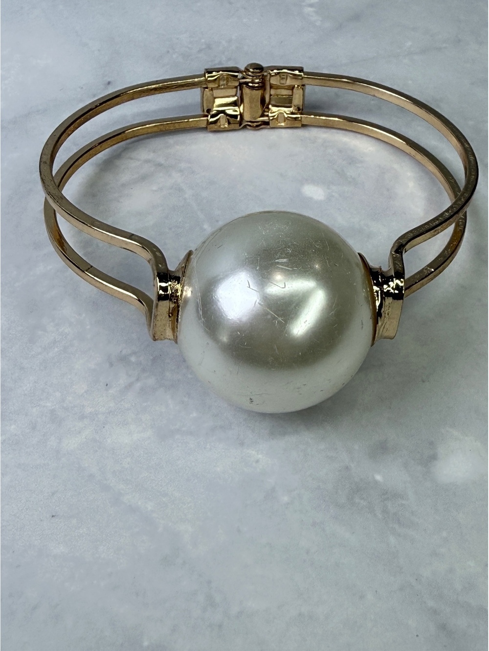 Gold tone cuff bracelet with oversized faux pearl
